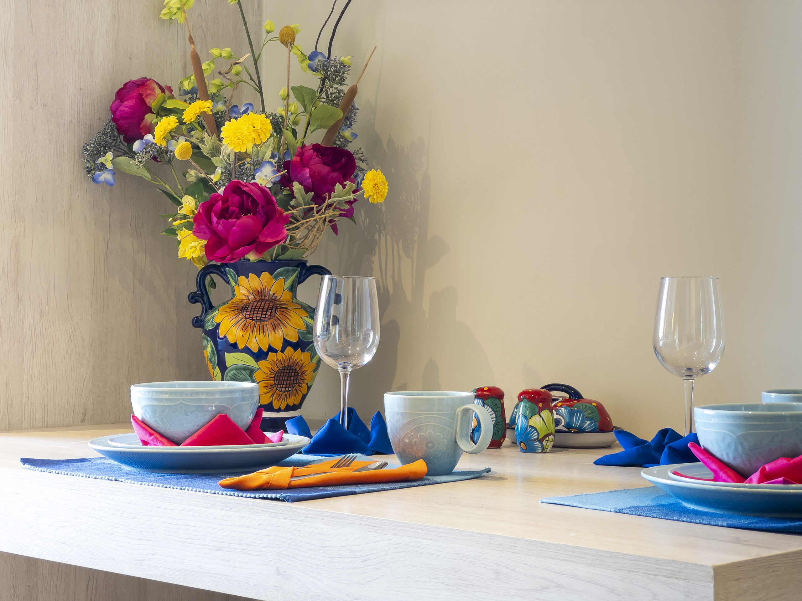 Dining table with colorful place settings and flowers.