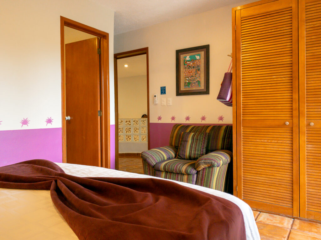 Striped armchair beside wooden closet doors and an open bathroom doorway.