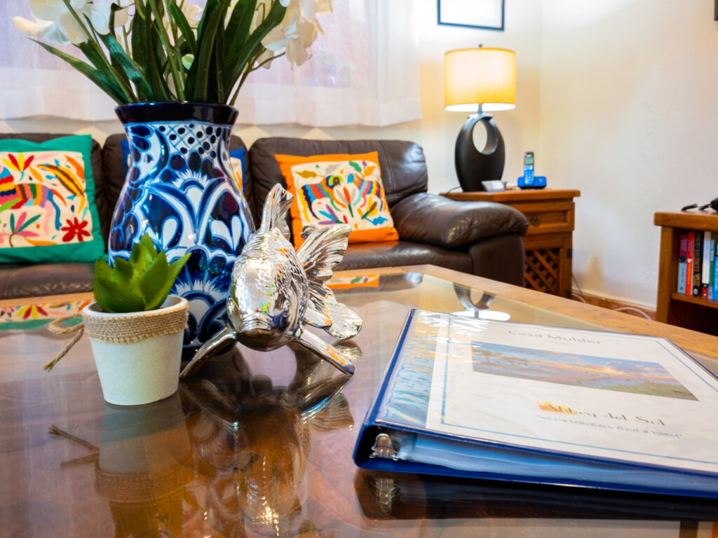 Flowers in a blue-and-white vase and a guest information binder on a wooden coffee table.