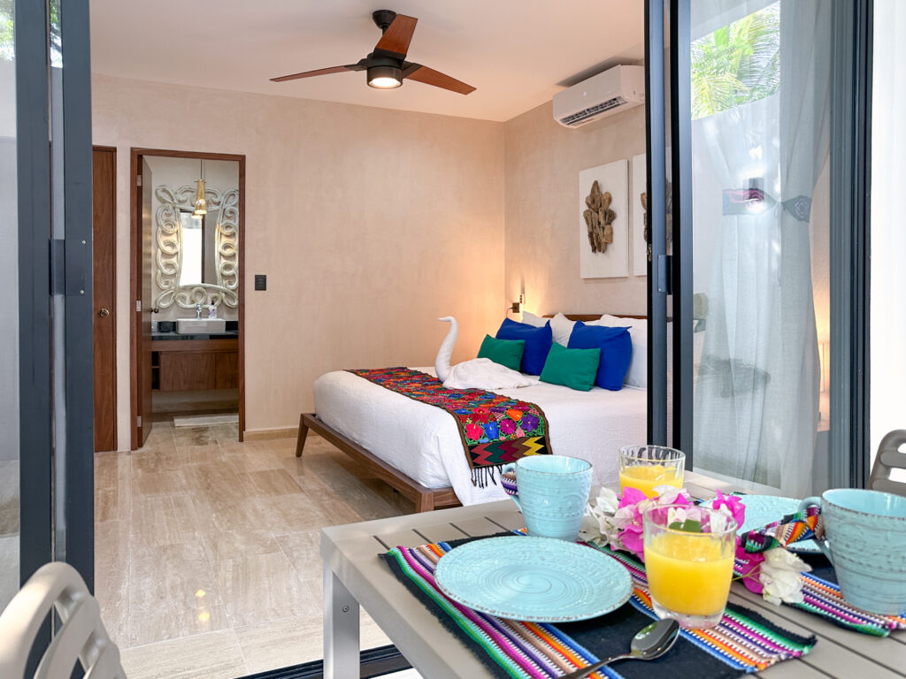 Outdoor table set with dishes and drinks in front of open bedroom doors.