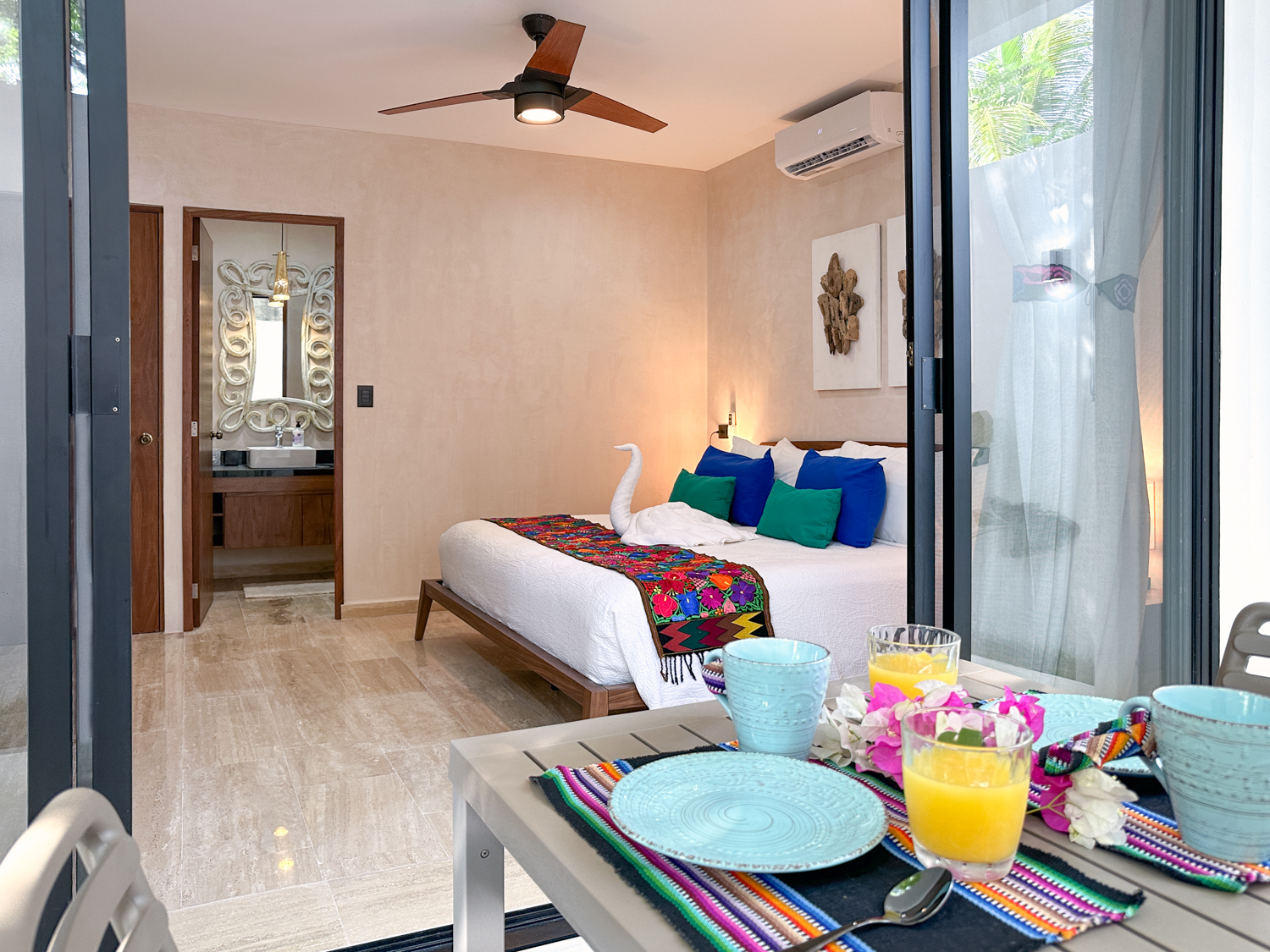 Outdoor table set with dishes and drinks in front of open bedroom doors.