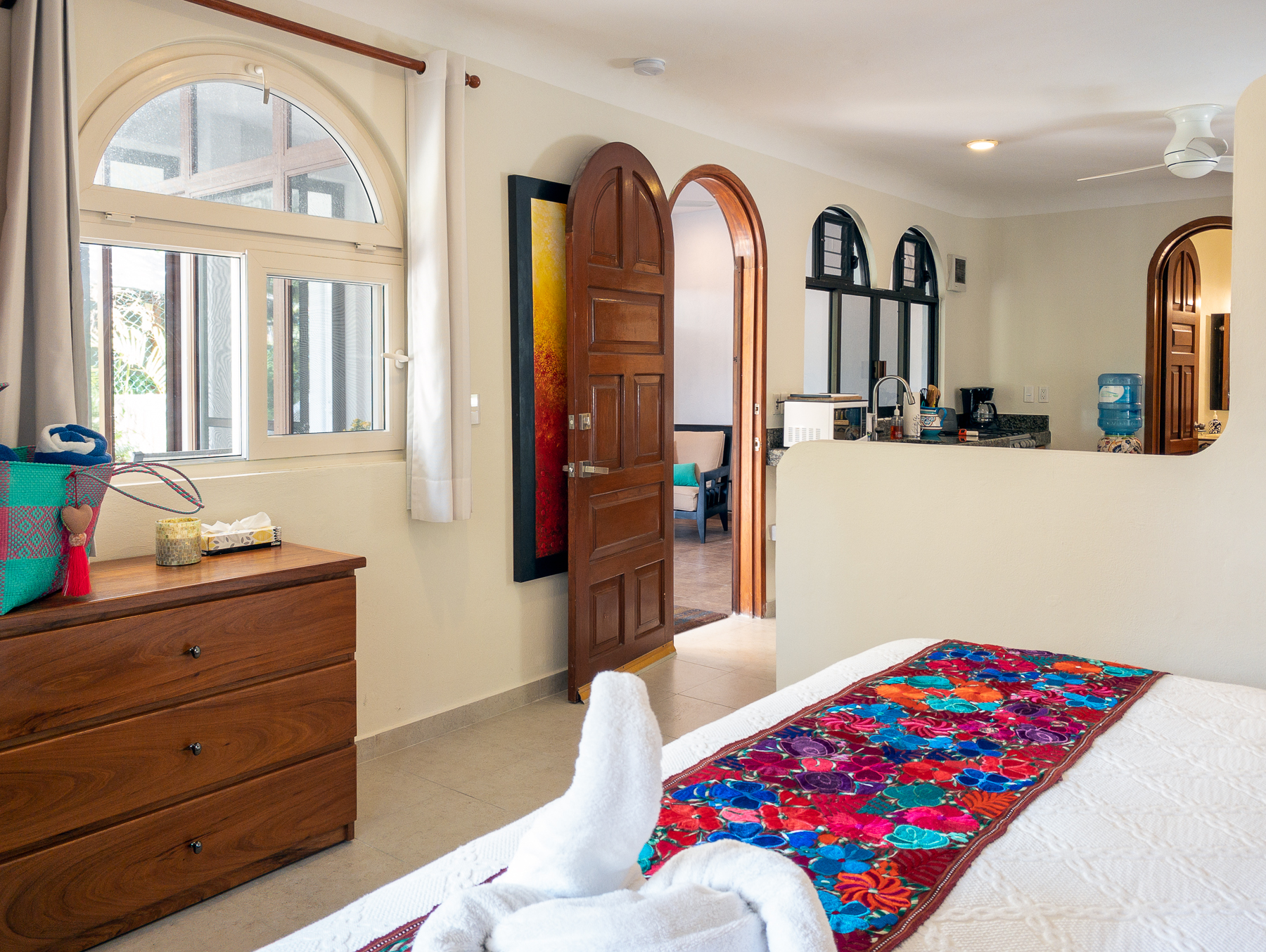 Bedroom with a floral runner and towel swan, looking toward the kitchen.