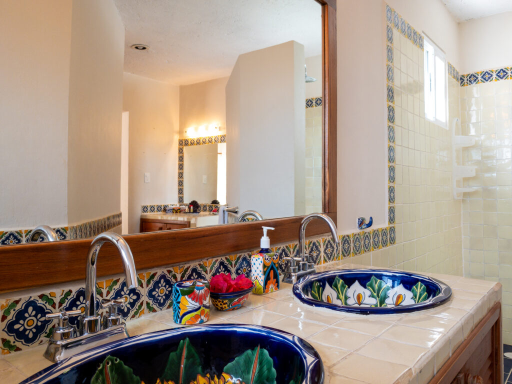 Two painted ceramic sinks set into a tiled bathroom counter beneath a large mirror.