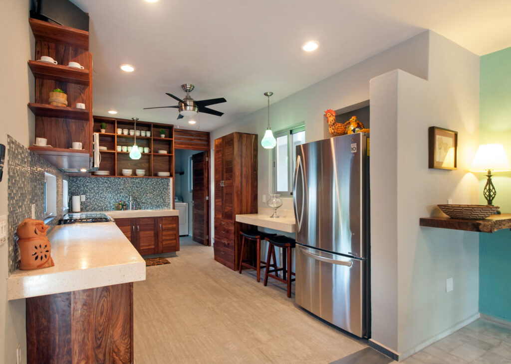 Kitchen cabinets and counters beside a stainless steel refrigerator and small breakfast counter.