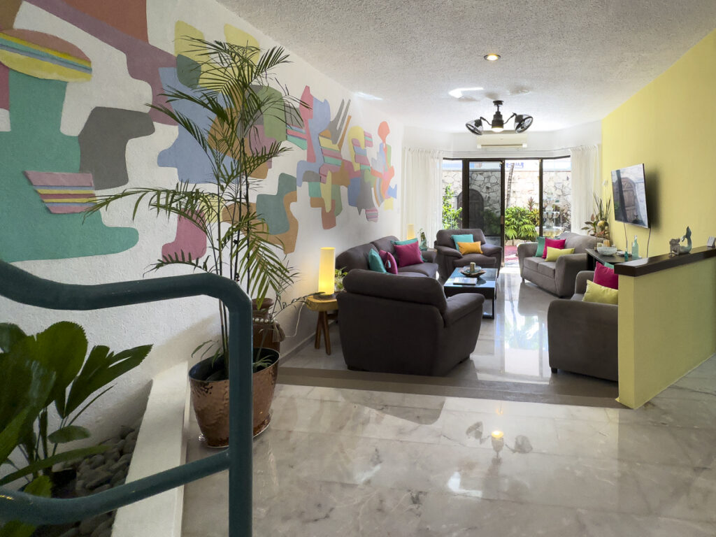 Steps lead down to a living room with gray seating beside a large abstract wall mural.