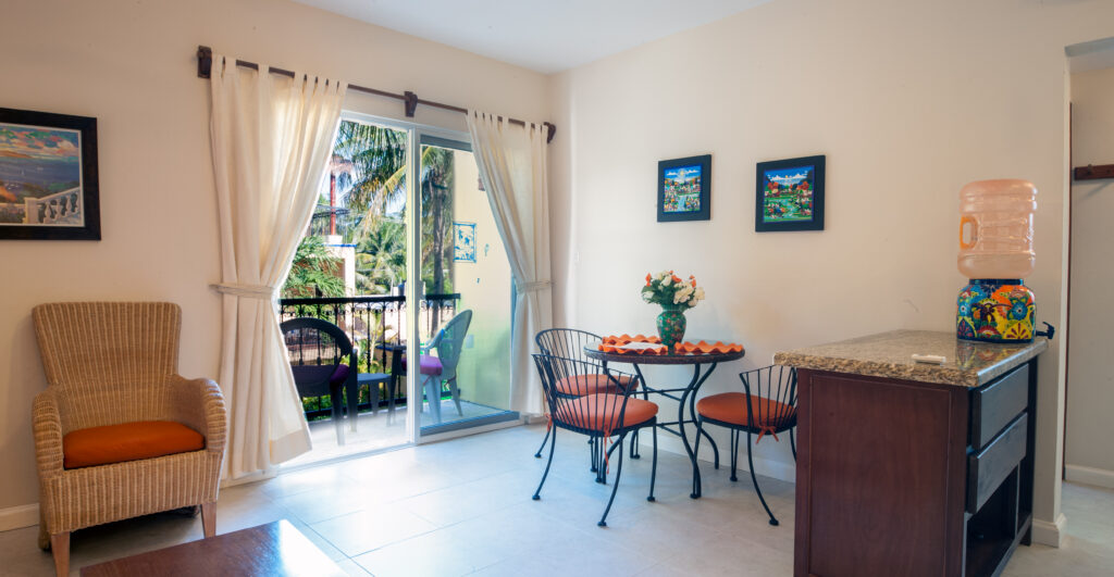 Round dining table and wicker chair beside a breakfast counter and sliding balcony doors.