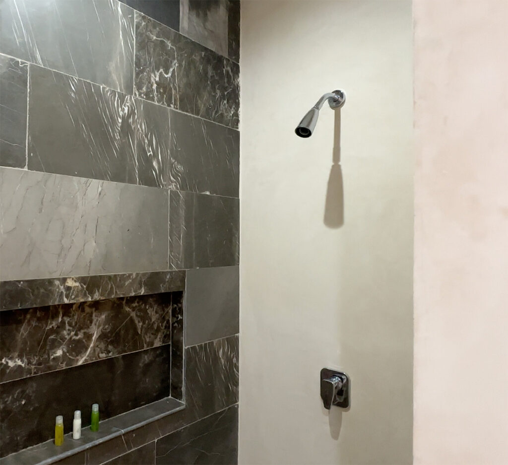 Shower with contrasting dark and light stone-look tiles, a recessed shelf, and black fixtures.