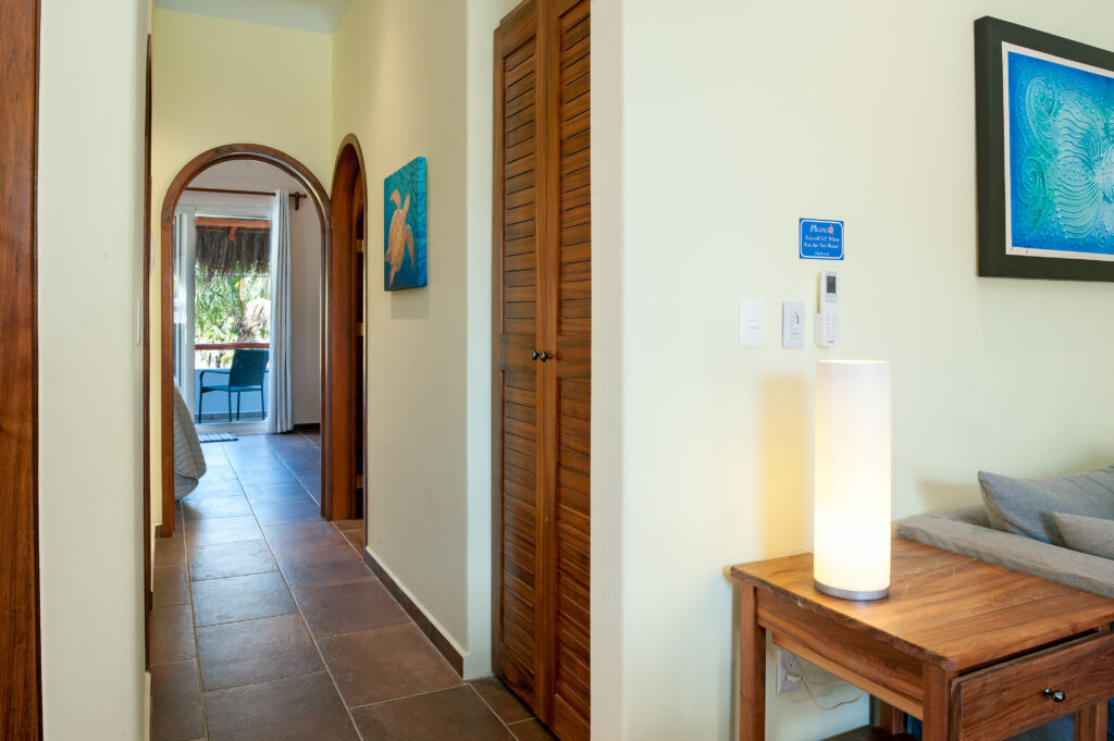 Hallway with wooden closet doors and an arched doorway leading toward a bedroom and balcony.