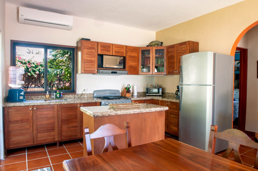 Kitchen with wooden cabinets, stove, refrigerator, and stone breakfast counter.
