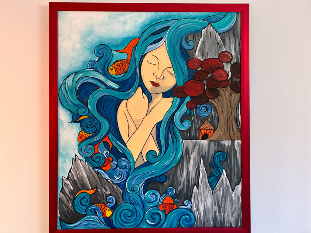Framed painting of a woman with flowing blue hair, flowers, and fish.