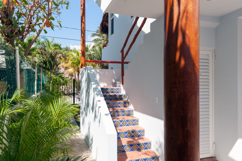Outdoor stairs with blue patterned tile risers beside white walls and tropical plants.