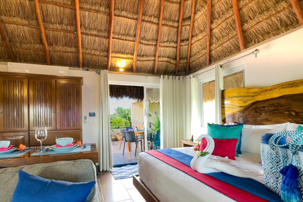 Bed and dining bar beside open sliding doors leading onto a plant-filled terrace.