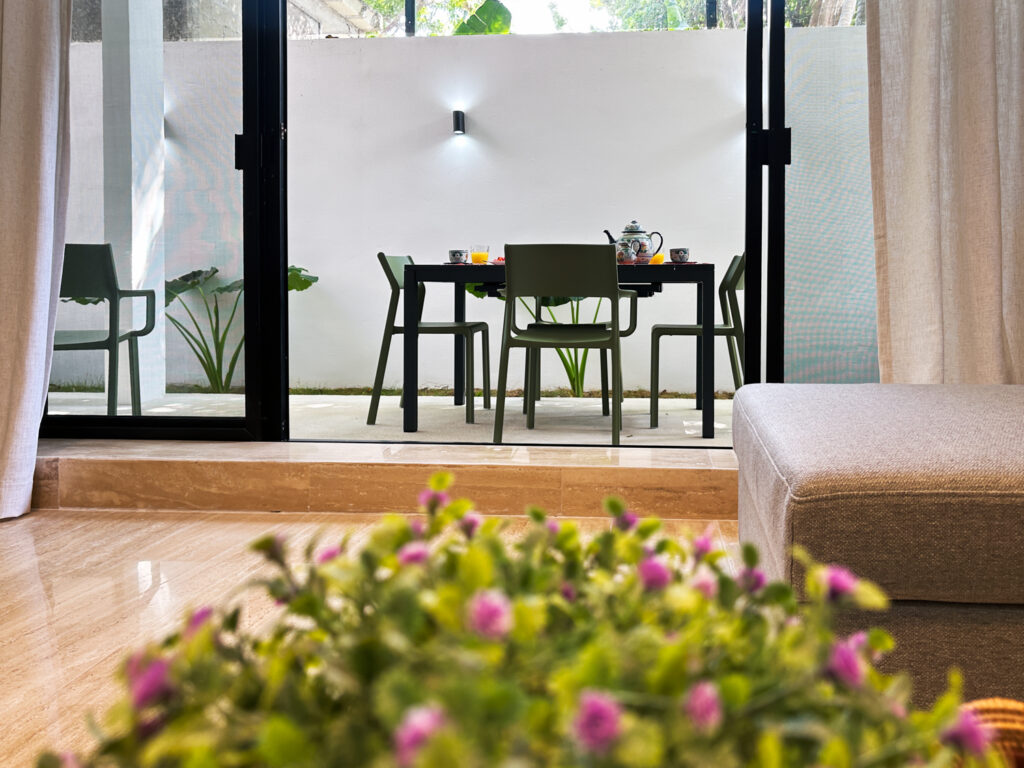 View from the living room through glass doors to a small outdoor dining table.
