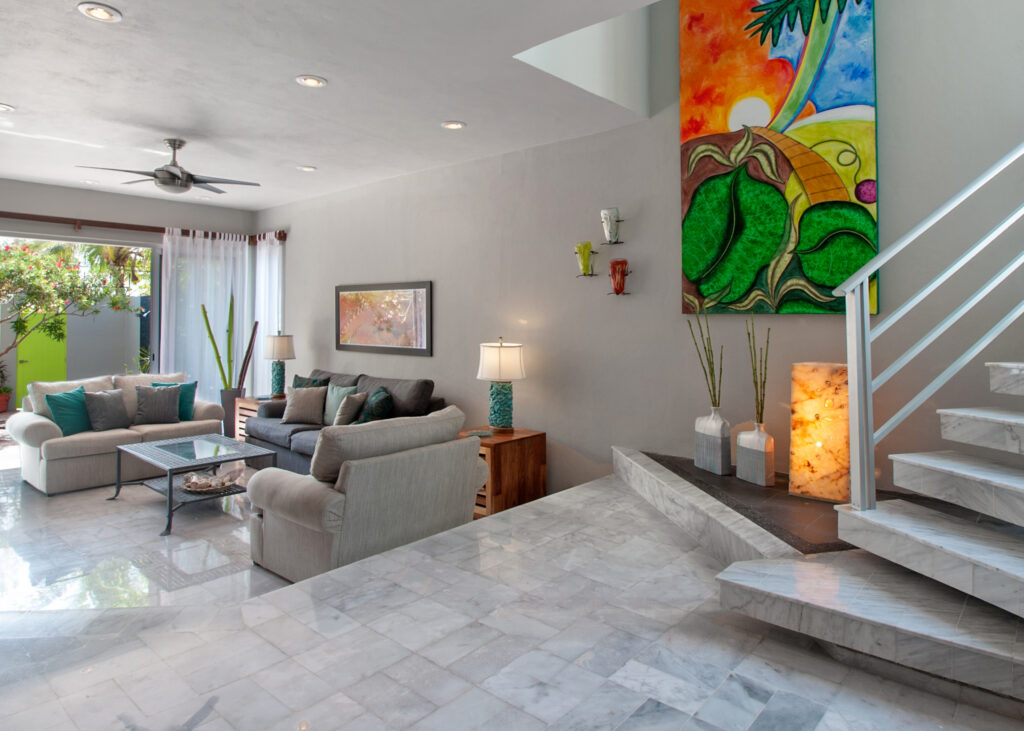 Steps from the entrance lead down to a living room with sofas and a glass coffee table.