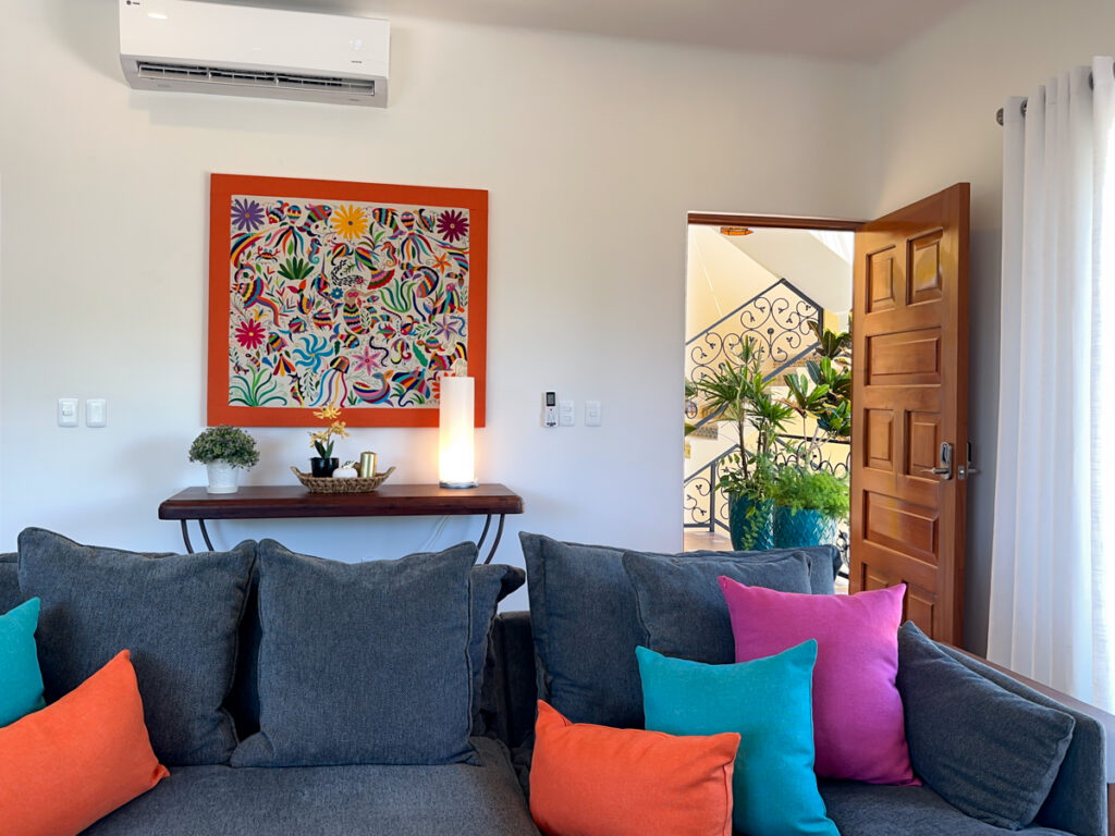 Colorful floral artwork above a narrow console behind the gray sectional sofa.