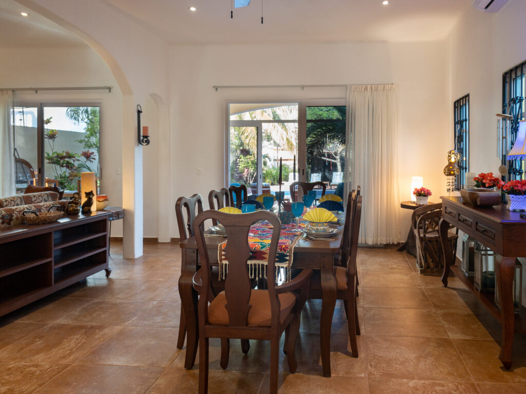 Long dining table with wooden chairs between sideboards near glass doors to the garden.