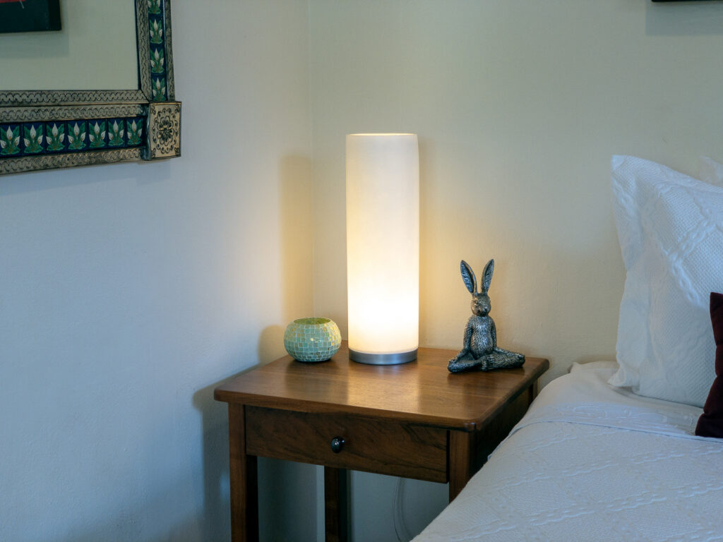 Glowing bedside lamp and a small rabbit figurine on a wooden nightstand.