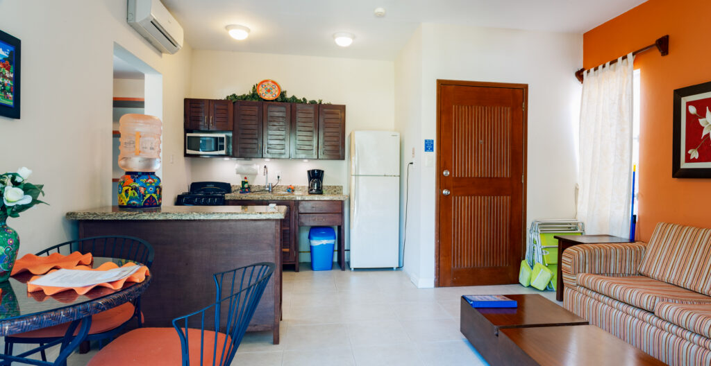 Striped sofa and coffee table facing an open kitchen with a breakfast counter and white refrigerator.