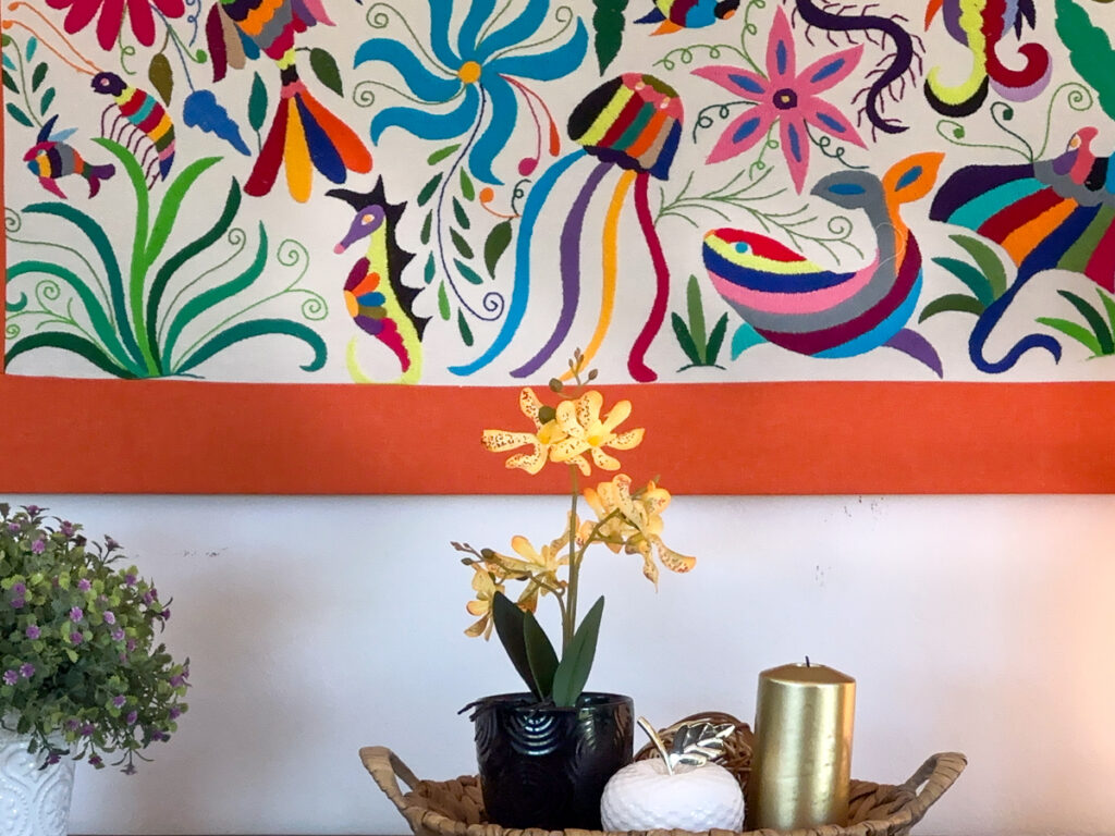 Close view of colorful birds and flowers in framed artwork above a small decorative arrangement.
