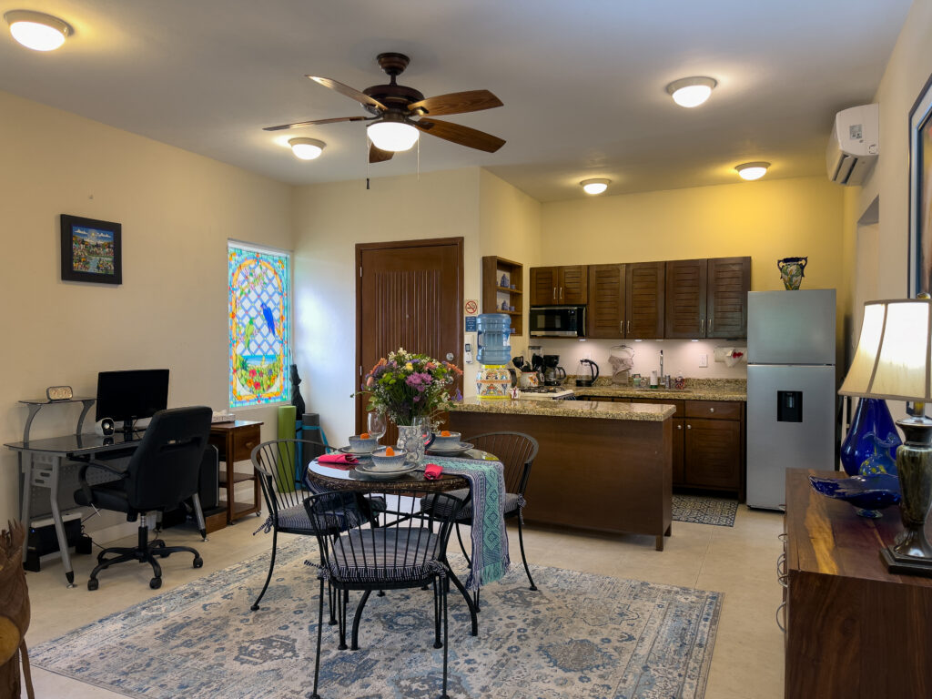 Kitchen and dining area with a round table, desktop computer, and decorative stained-glass window.