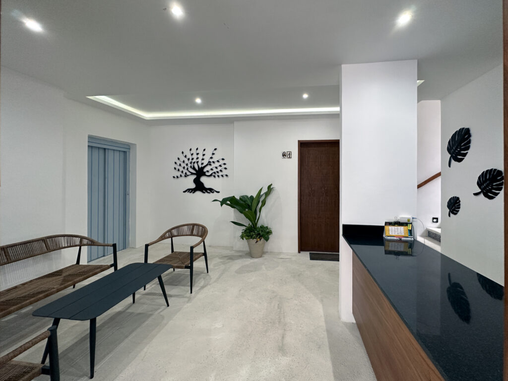Chairs and a bench in a bright entrance lobby with decorative wall art and a potted plant.