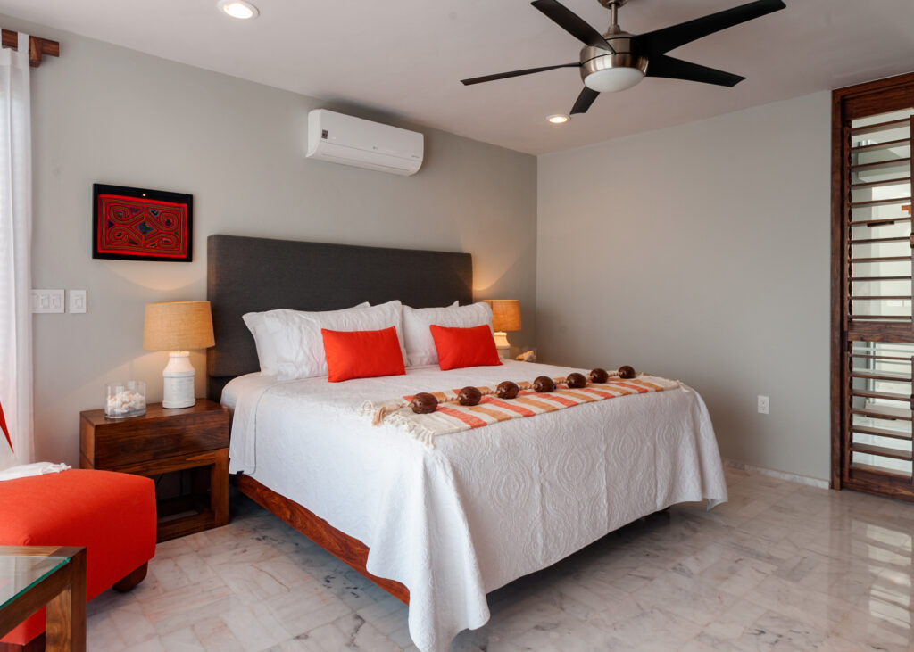 Bed with orange accents and matching wooden nightstands beneath a ceiling fan.