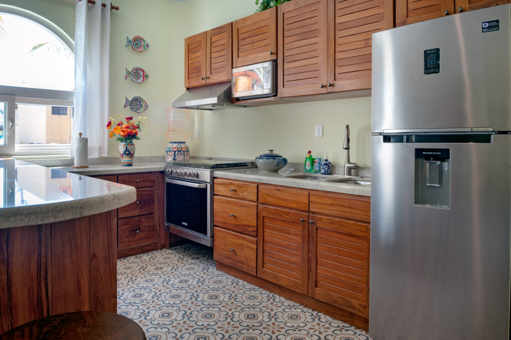Kitchen with wooden cabinets, microwave, stove, sink, and stainless steel refrigerator.