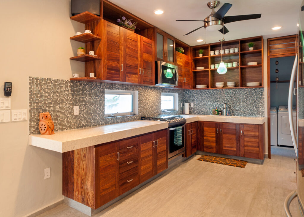 Kitchen with extensive wooden cabinets, mosaic tile backsplash, stove, and pale countertops.