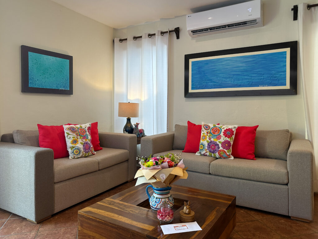 Two sofas with red and patterned cushions beneath framed blue artwork.