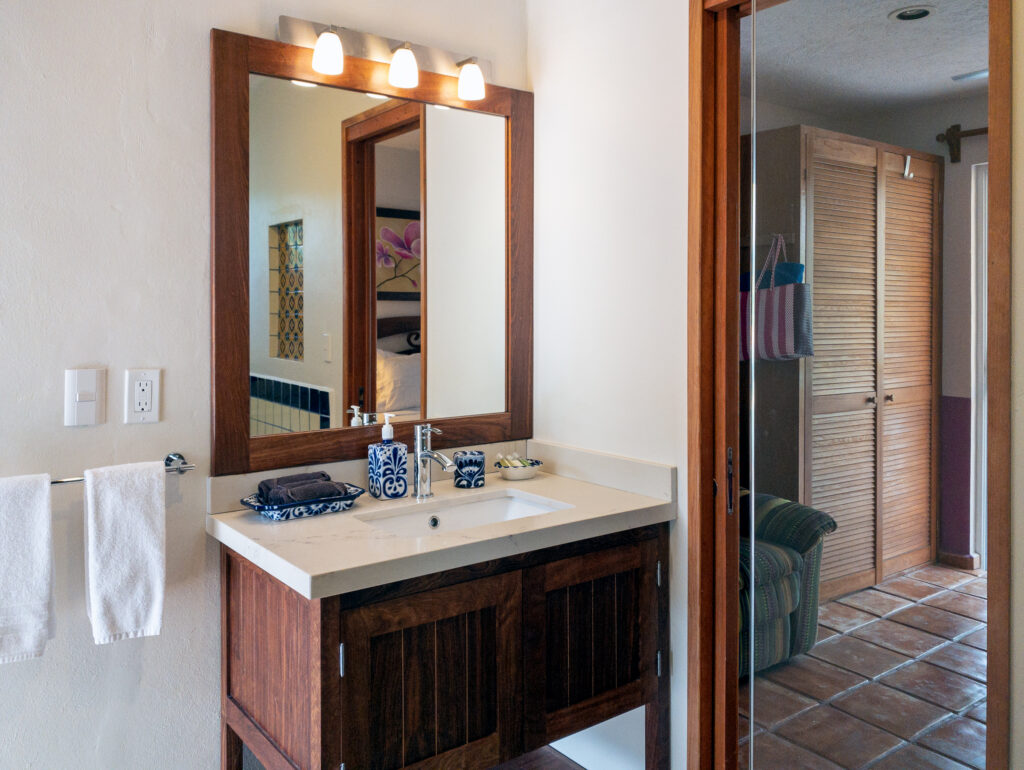 White rectangular basin over wooden cabinets beneath a framed mirror beside an open doorway.
